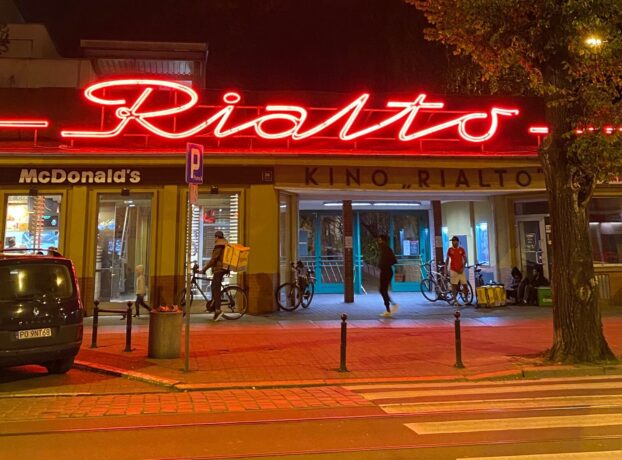 Grafika artykułu: Na zdjęciu wejście do kina Rialto wykonane wieczorem. Nad wejściem czerwony, zapalony neon z napisem "Rialto".