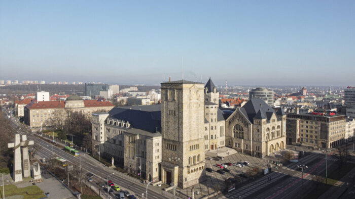 Zdjęcie Zamku z lotu ptaka - widać cały budynek, fotografia wykonana w słoneczny dzień, w tle widać panoramę miasta.