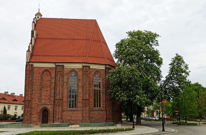 Grafika artykułu: Na zdjęciu kościół NMP na Ostrowie Tumskim, po prawej stronie widać fragment uliczki z drzewami, po lewej stronie za kościołem widać fragment białego budynku. 