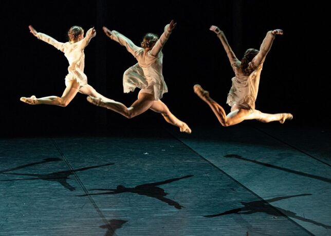 Grafika artykułu: Na zdjęciu baletnice tańczące podczas spektaklu „Egle, królowa węży”, wszystkie unoszą się nad ziemią, mają uniesione ręce.