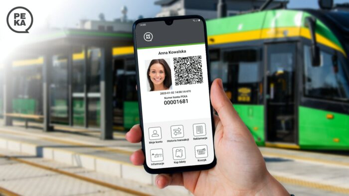 Grafika artykułu: w centrum dłoń trzymająca smartfon, na ekranie poglądowy wygląd zmodernizowanej aplikacji. W tle zatrzymany przy przystanku tramwaj.