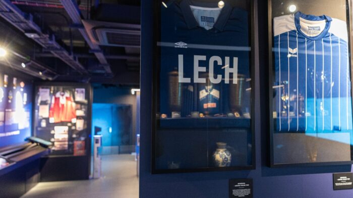 Grafika artykułu: na zdjęciu ekspozycja Muzeum Lecha. Na pierwszym planie koszulki klubu zawieszone w antyramach.