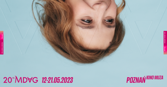 Grafika artykułu: w centrum na błękitnym tle zdjęcie części twarzy kobiety, ma miedziane włosy, wzrok skierowany w prawa stronę, zdjęcie jest odwrócone do góry nogami, na dole grafiki różowe napisy "20th MDAG 12-21.05.2023", "Poznań Kino Muza". 