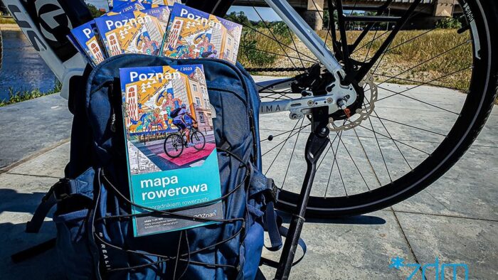 Grafika artykułu: na zdjęciu fragment roweru, o pedał oparty jest granatowy plecak, z którego wystają rowerowe mapy Poznania.
